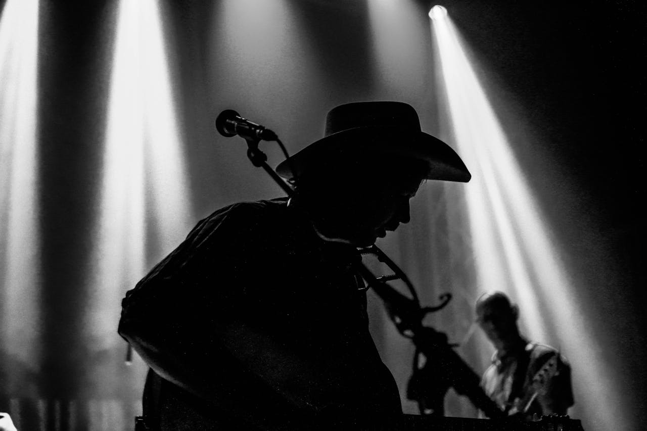 Silhouette of musicians during a live country music performance with dramatic stage lighting.